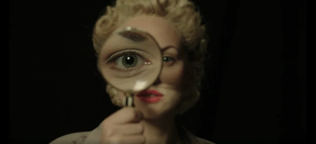 Elvira Slate investigator holding a magnifying glass up which enlarges eye